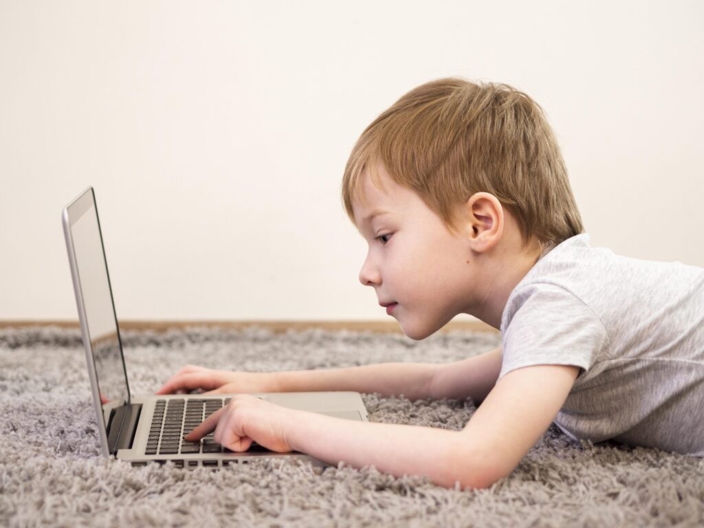 sideways little boy playing his laptop scaled 1